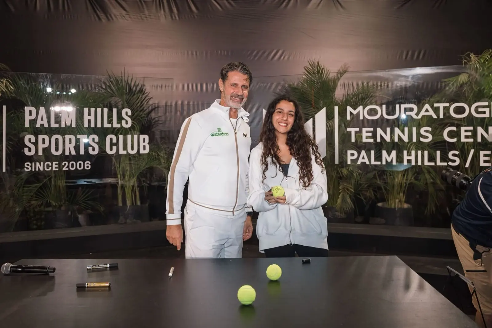 Patrick Mouratoglou con un joven jugador que sostiene una pelota de tenis firmada en Palm Hills