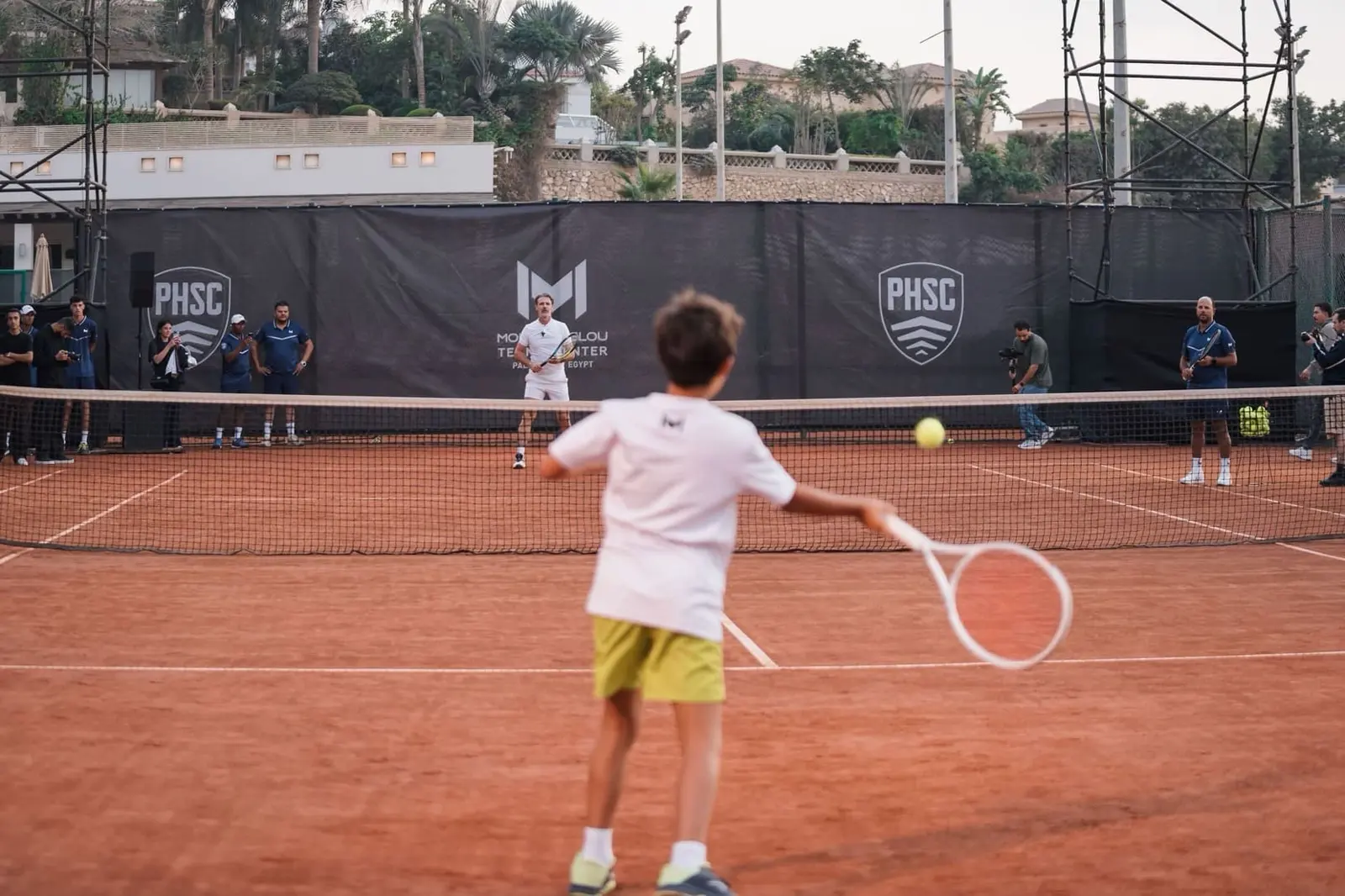 Junger Spieler spielt eine Vorhand gegen Patrick Mouratoglou auf einem Sandplatz im Mouratoglou Tennis Center Palm Hills