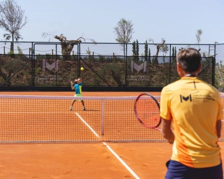 Un coach che allena un giovane giocatore su un campo in terra battuta