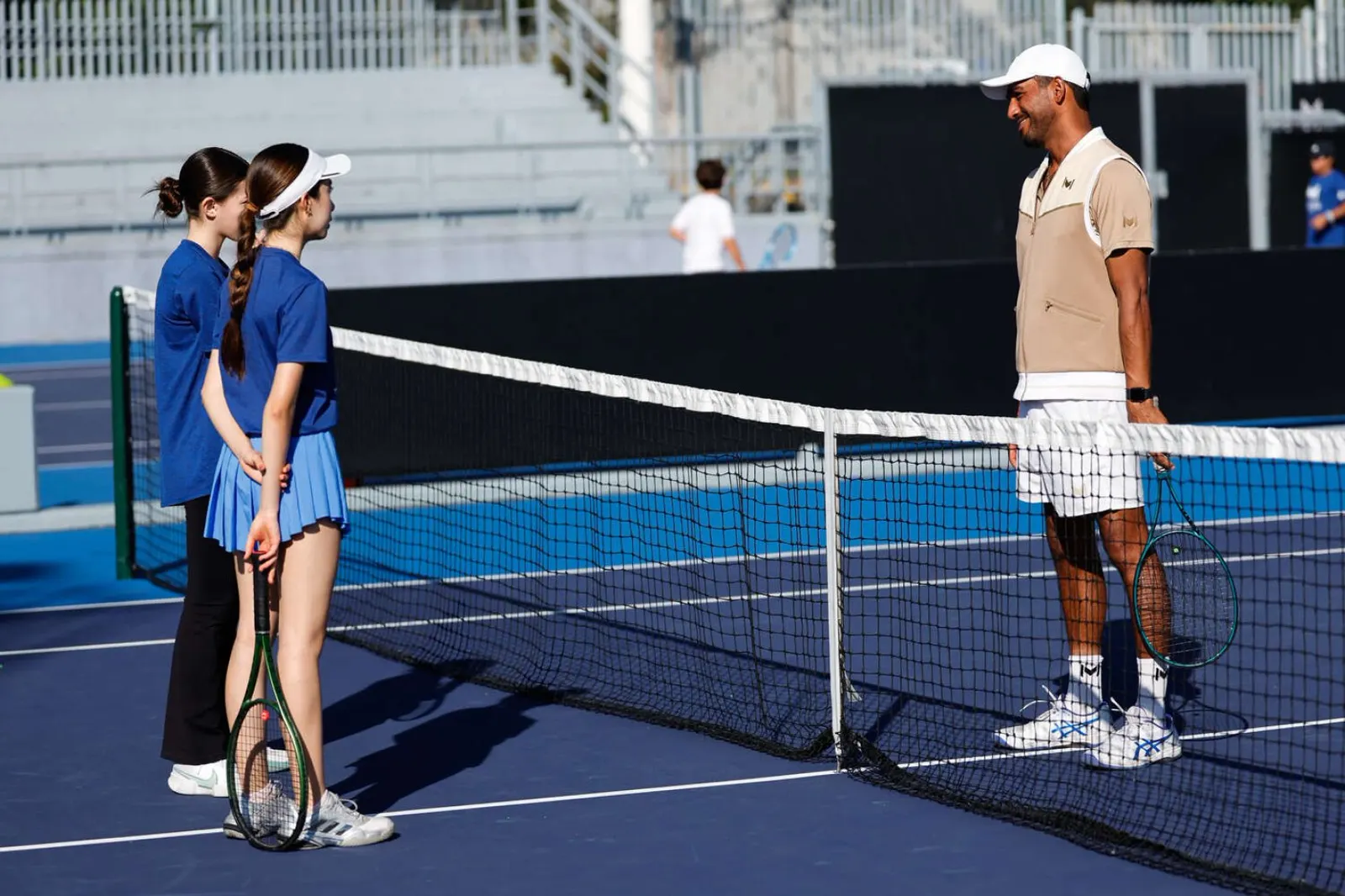Deux jeunes joueurs écoutant leur coach au filet sur un court bleu à Guadalajara