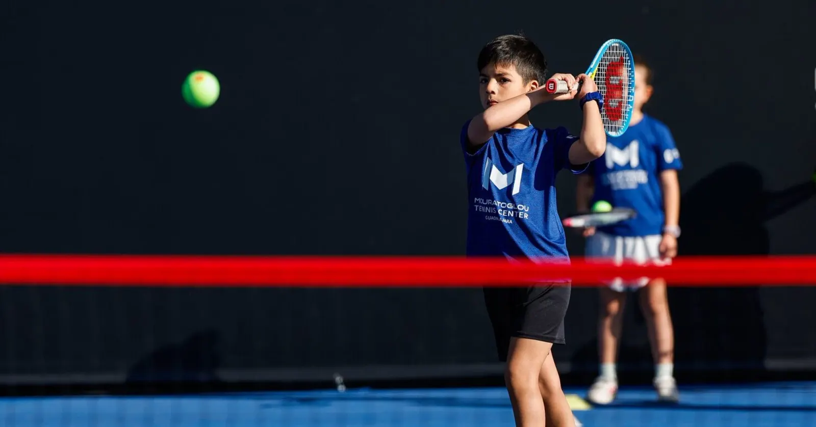 Jugador junior golpeando un revés a dos manos durante un entrenamiento en el Mouratoglou Tennis Center Guadalajara
