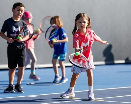Jeunes enfants pratiquant le mini-tennis sur un court bleu à Guadalajara.