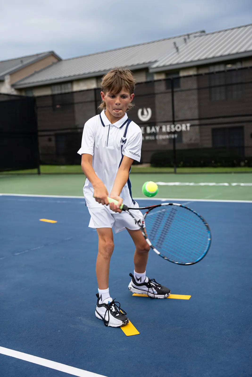 Niño jugando al tenis en una pista exterior