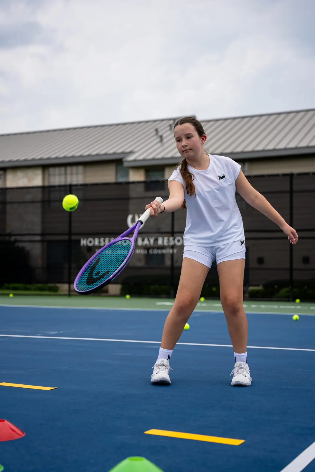 Niña jugando al tenis en una pista exterior