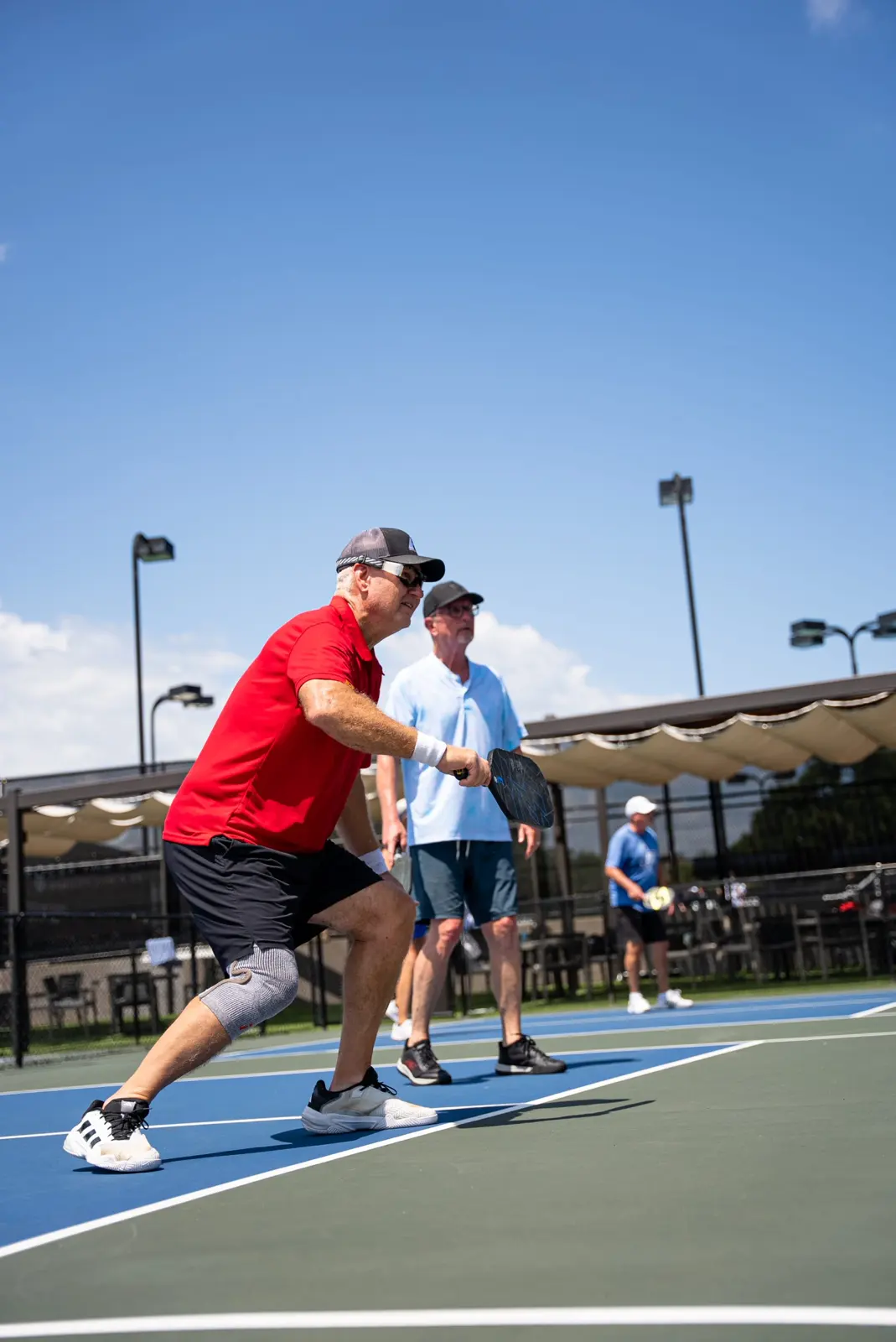 Due adulti che giocano a pickleball su un campo all’aperto sotto il sole
