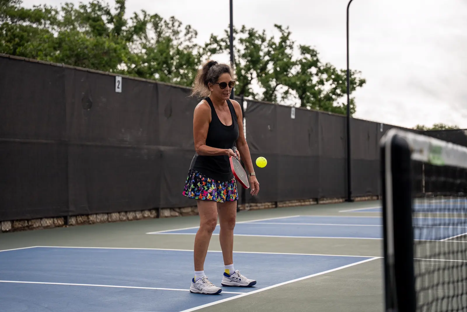 Una donna che gioca a pickleball su un campo all’aperto