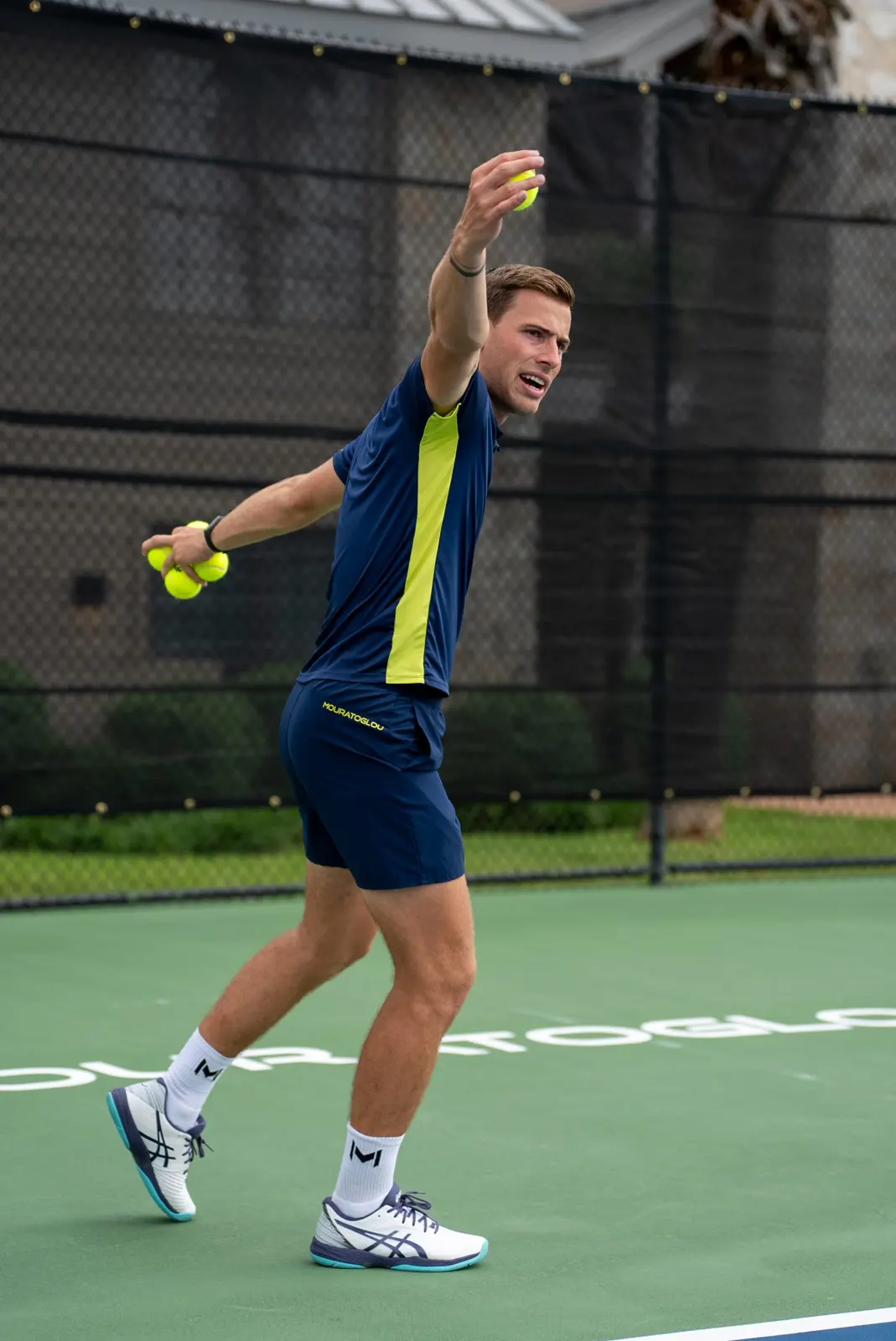 Un entrenador de tenis mostrando un revés en una pista exterior