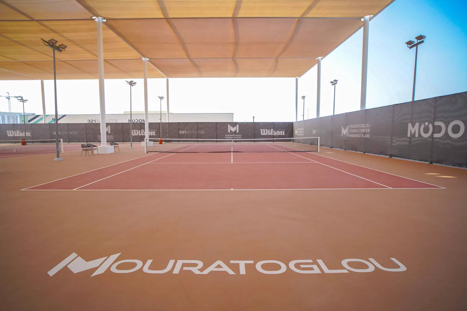 Pistas semicubiertas con el nombre Mouratoglou pintado en el suelo en el Mouratoglou Tennis Center Hudayriyat Island de Abu Dabi.