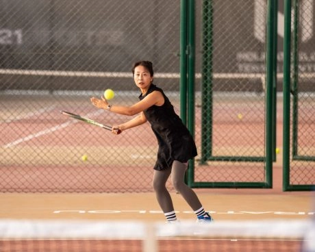 Jugador adulto entrenando en las pistas de tenis del Mouratoglou Tennis Center Hudayriyat Island de Abu Dabi, entre la brisa marina y las palmeras.