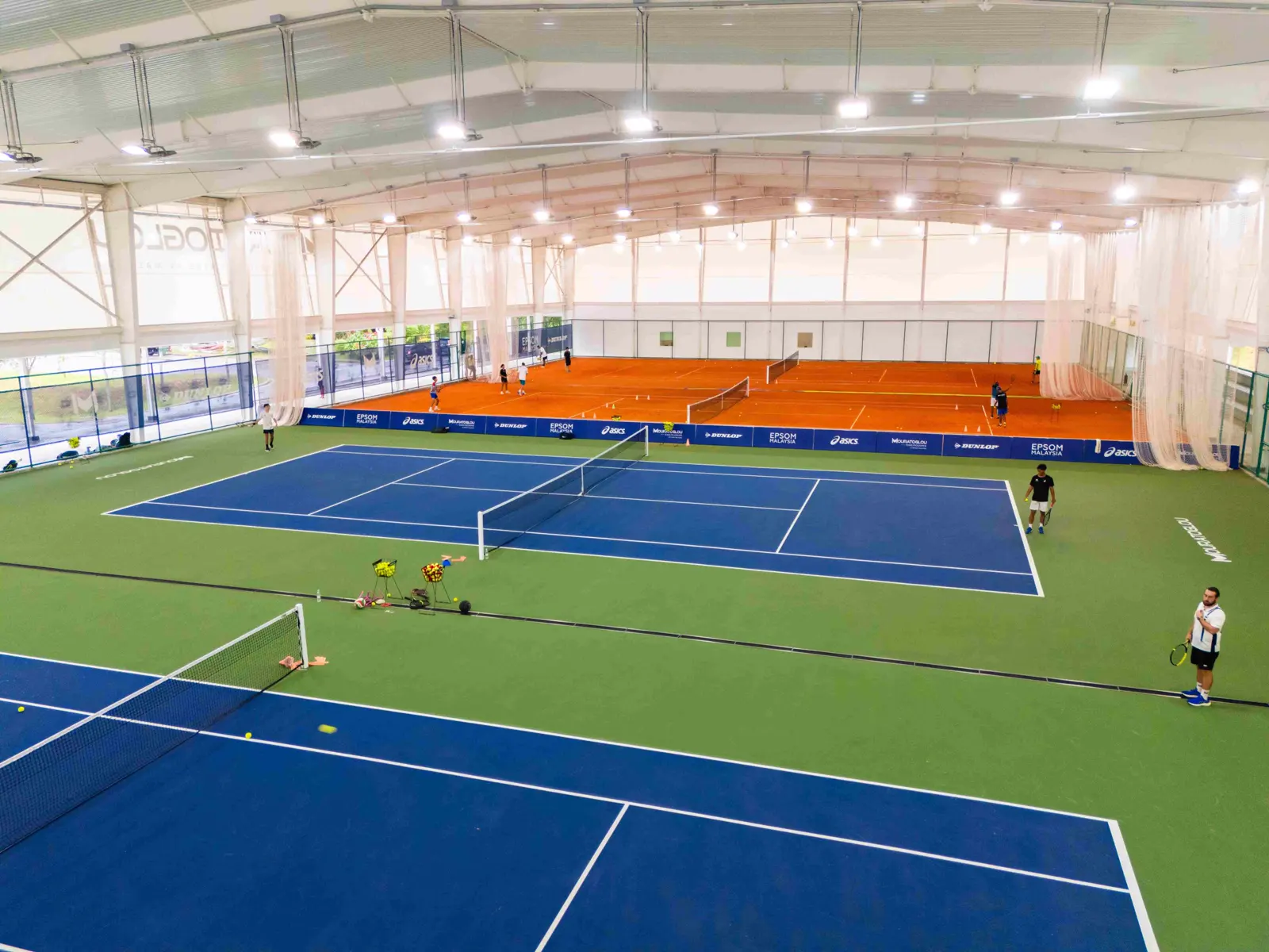 Installation de tennis couverte avec courts en dur bleus et courts en terre battue à la Mouratoglou Academy Malaysia