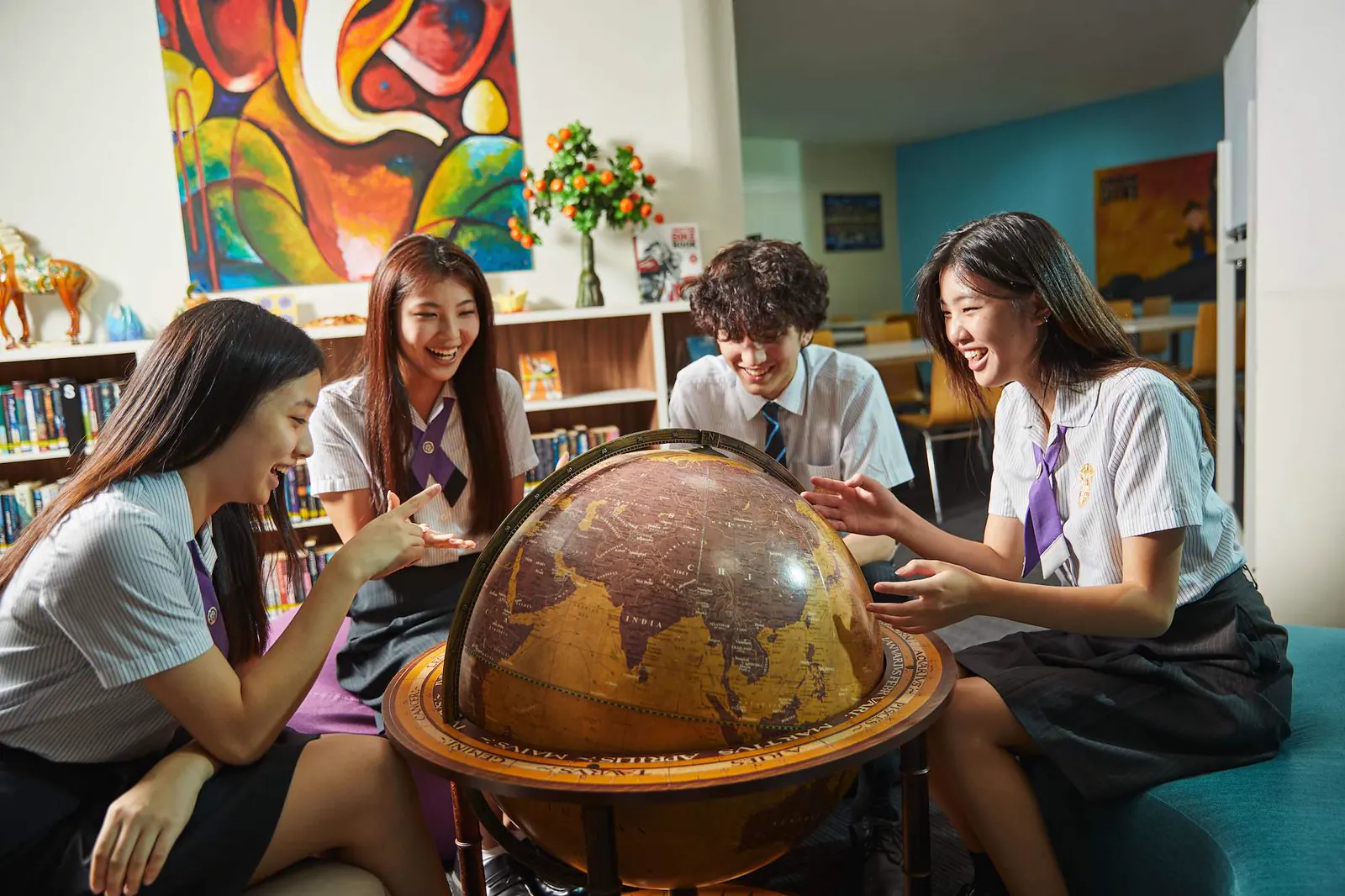 Schüler versammelt um einen Globus in der Bibliothek am Epsom College in Malaysia.