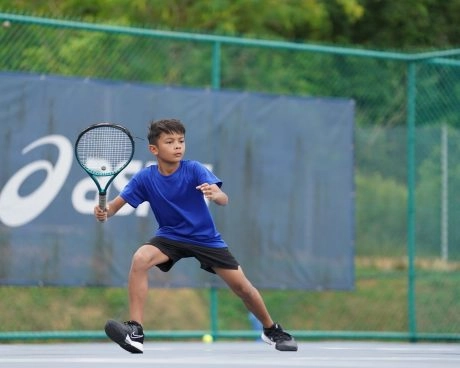 Junger Tennisspieler bereitet eine Vorhand auf einem Außenplatz vor.