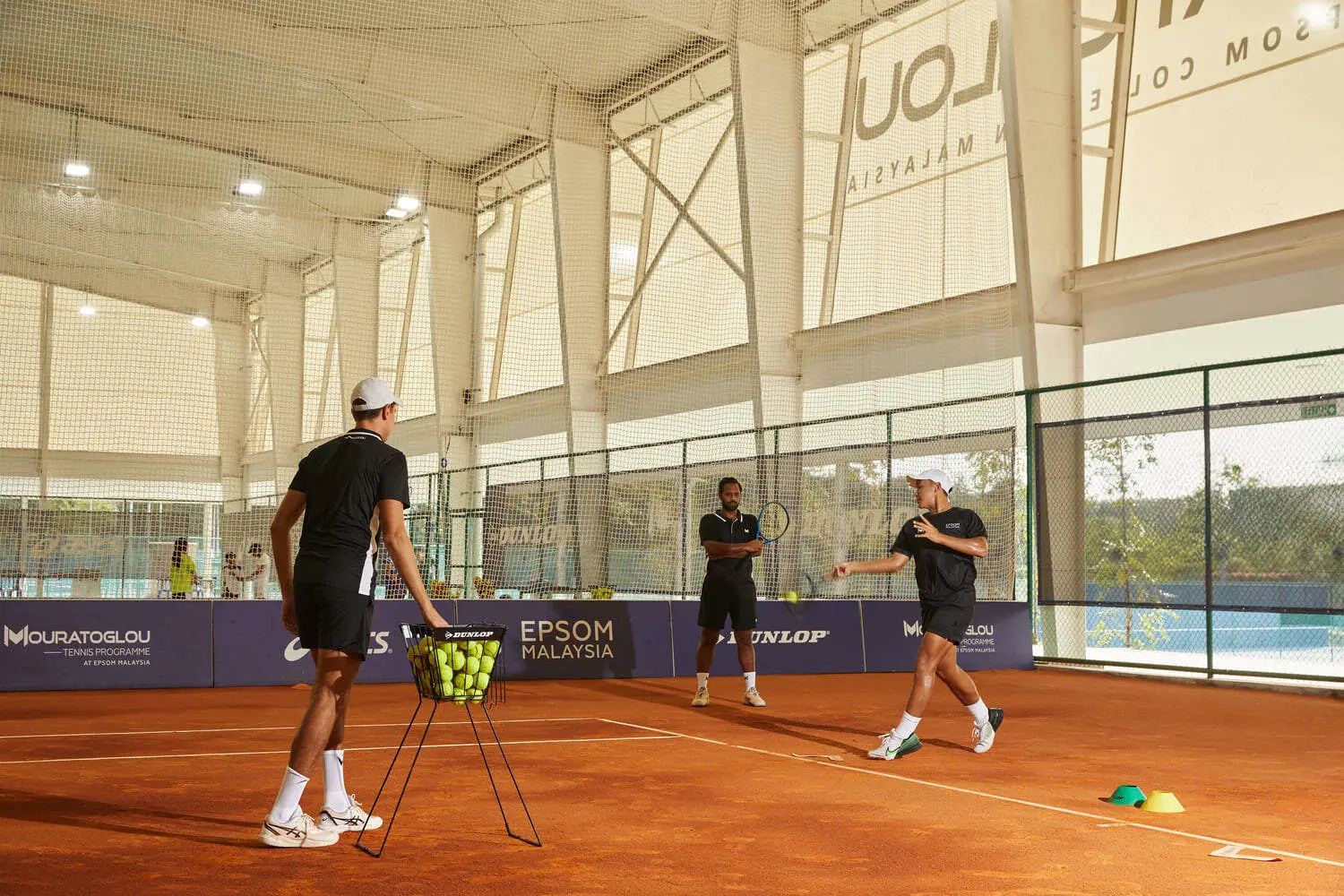Jugadores entrenando en las pistas cubiertas de tierra batida durante una sesión en la Mouratoglou Academy Malaysia