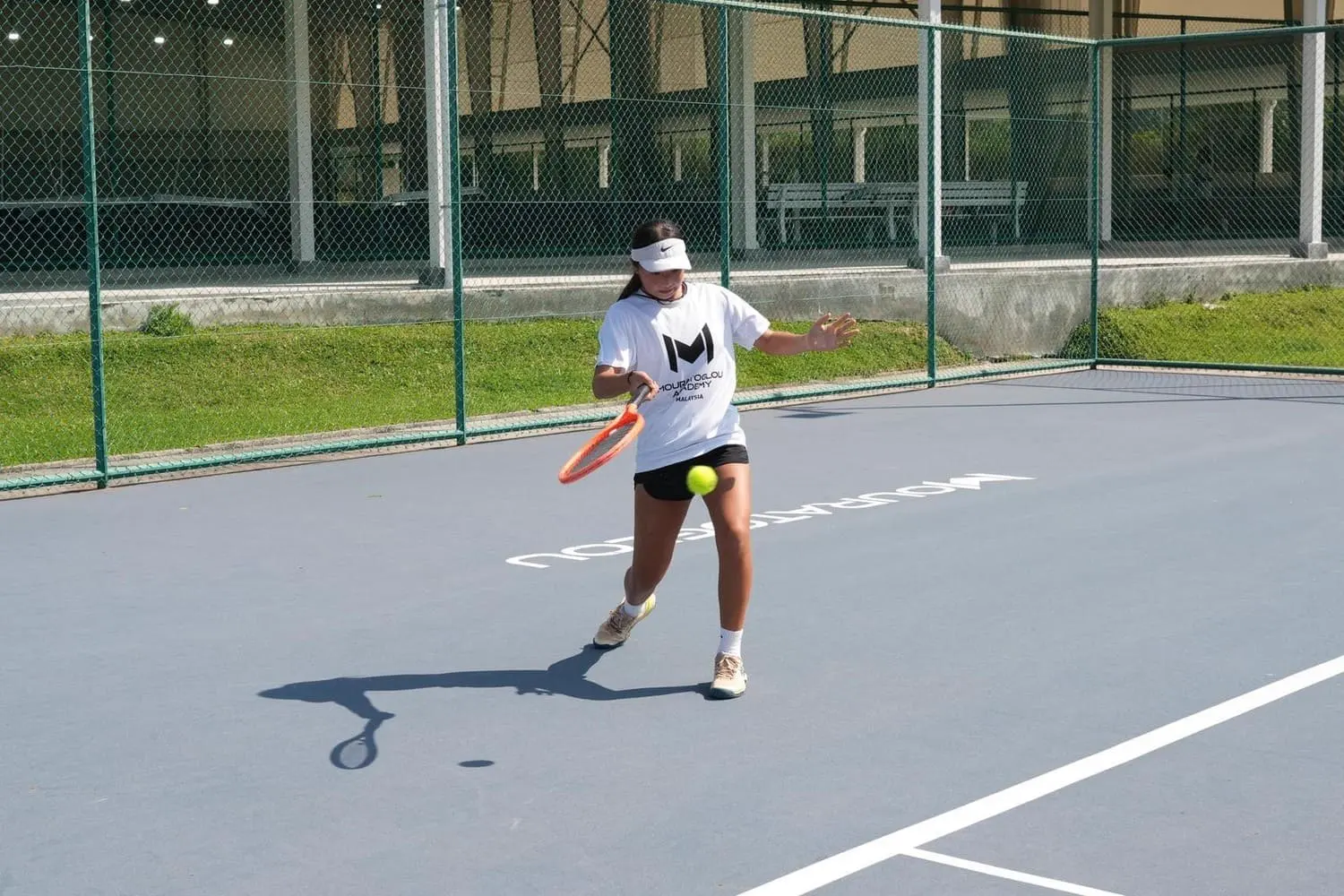 Élève frappant la balle sur un court en dur à la Mouratoglou Academy Malaysia