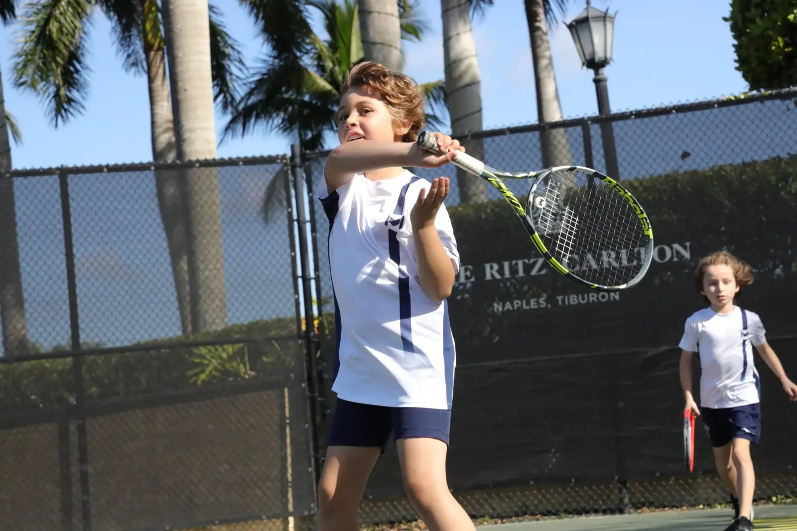 Junger Spieler übt den Aufschlag auf dem Platz im The Ritz-Carlton Naples, Tiburón.