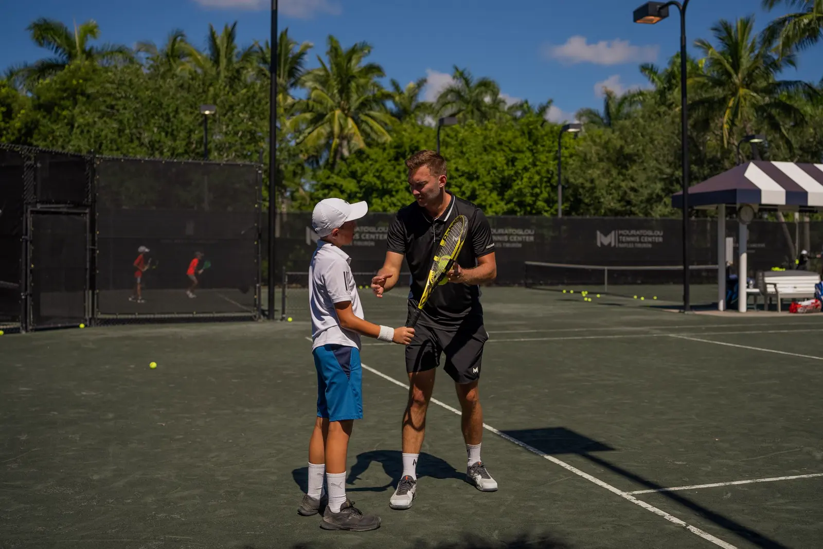 Junger Tennisspieler hört den Anweisungen seines Coaches im Mouratoglou Tennis Center Naples zu