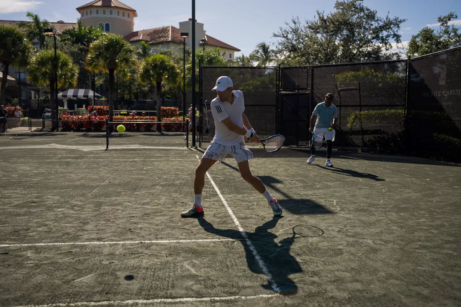 Spieler trainieren auf einem von Palmen umgebenen Sandplatz im Freien in Naples