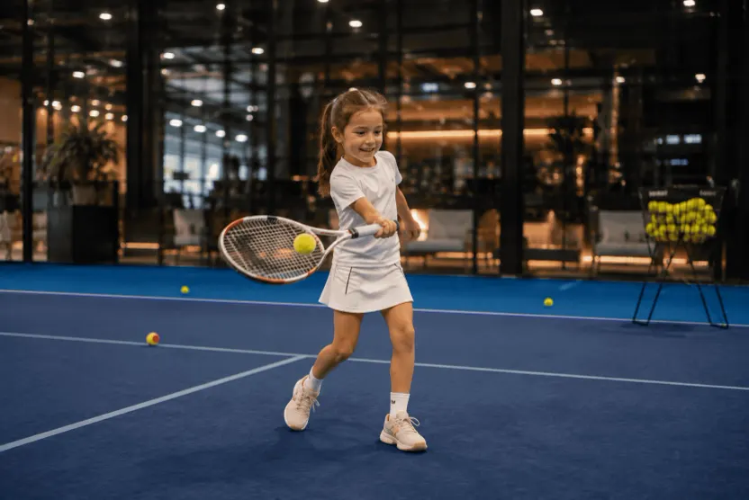 Junges Mädchen schlägt eine Vorhand auf einem Indoor-Minitennisplatz