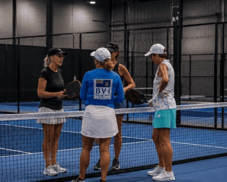 Jugadores encontrándose en la red en una pista de pickleball cubierta.