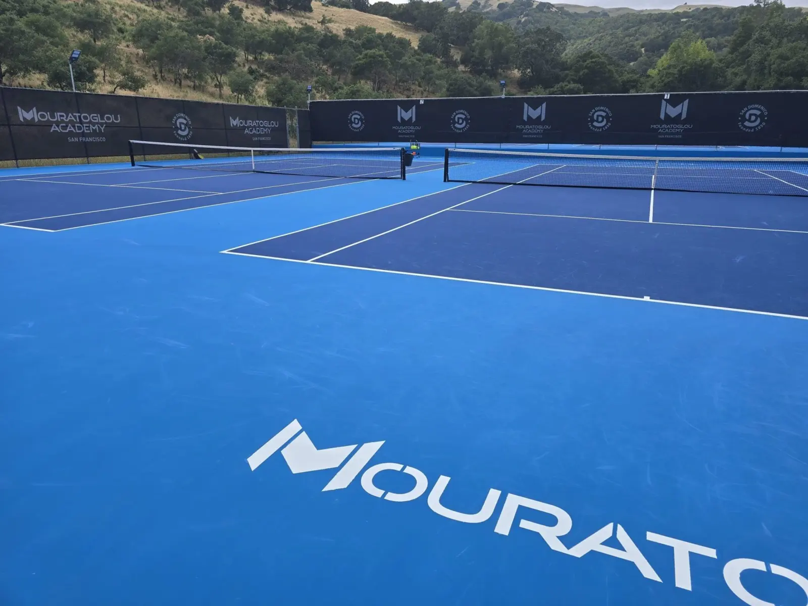 Courts en dur bleus portant le nom Mouratoglou à la Mouratoglou Academy San Francisco