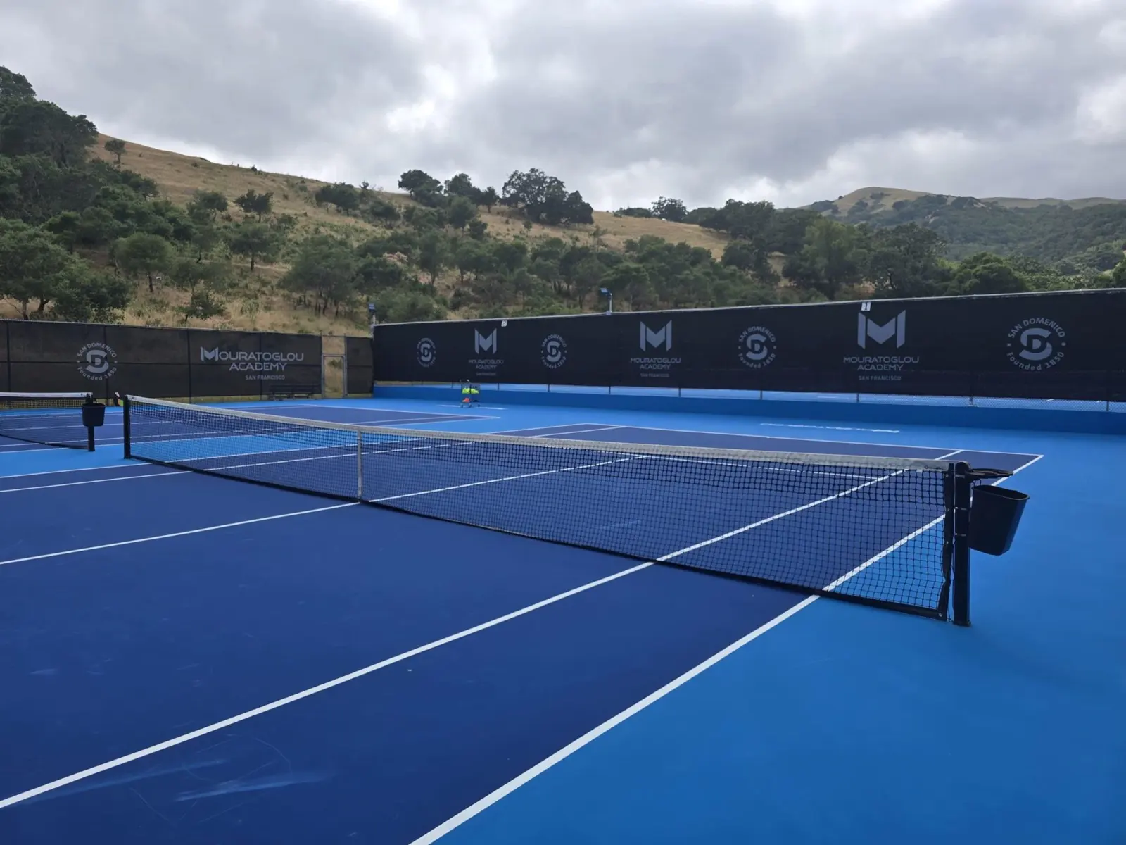Outdoor hard tennis courts surrounded by rolling hills at Mouratoglou Academy San Francisco