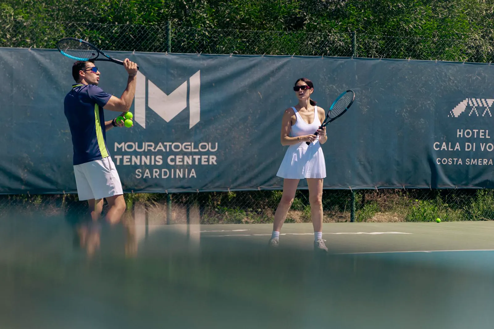 Spieler vor dem Banner des Mouratoglou Tennis Center Sardinia im Hotel Cala di Volpe.