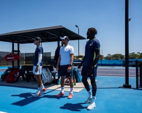 Coach discutant avec des joueurs sur un court en dur bleu du Mouratoglou Tennis Center Templeton.