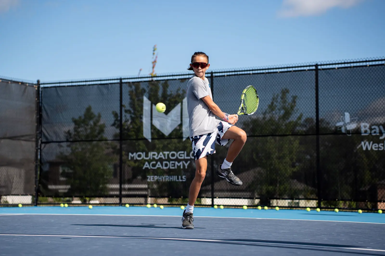 Giovane tennista salta per colpire un dritto durante un allenamento alla Mouratoglou Academy Zephyrhills