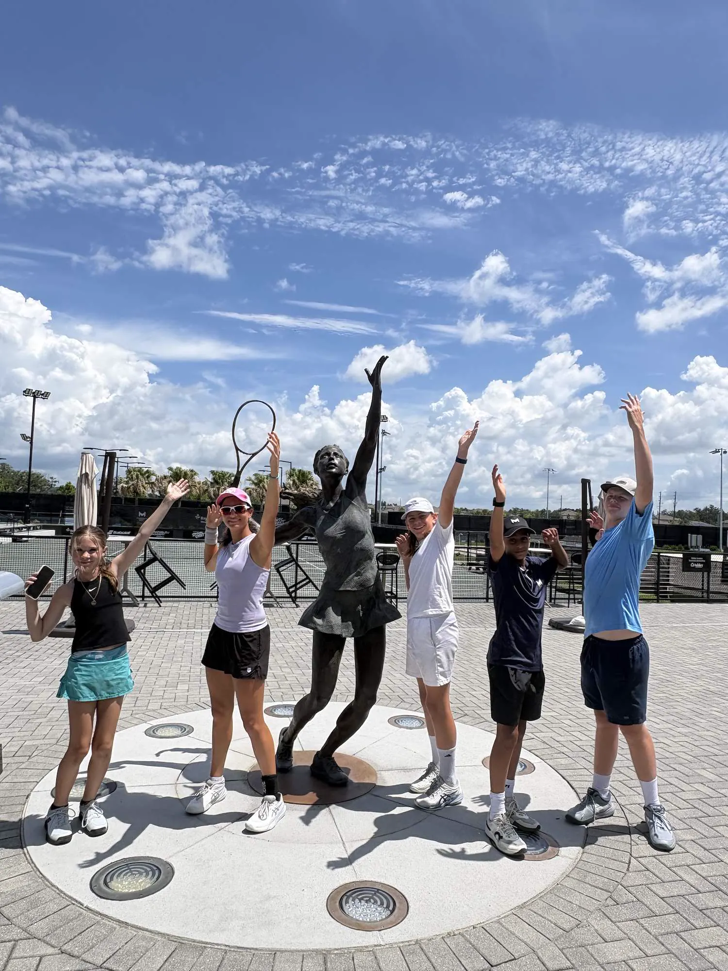 Gruppe von Spielern springt vor Freude auf den Plätzen der Mouratoglou Academy Zephyrhills.