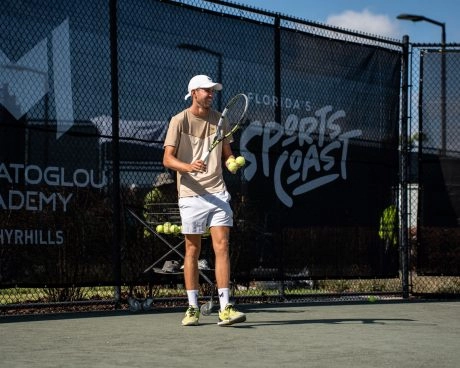 Tennistrainer mit Bällen und Schläger auf dem Platz an der Mouratoglou Academy Zephyrhills, Florida.