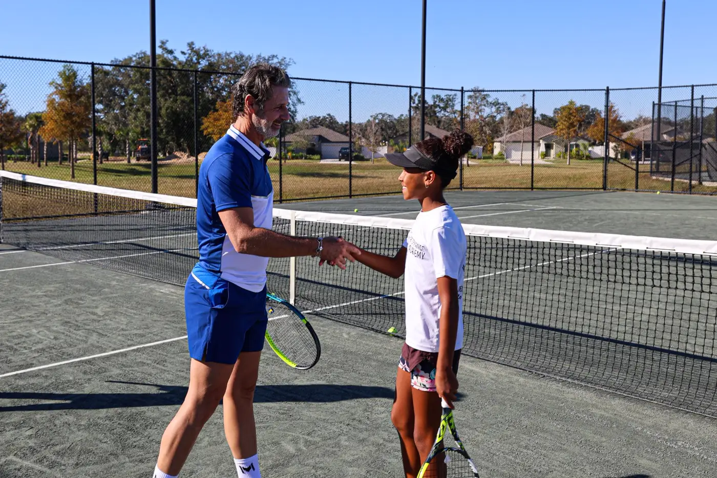 Patrick Mouratoglou stringe la mano a un giovane giocatore in campo alla Mouratoglou Academy Zephyrhills