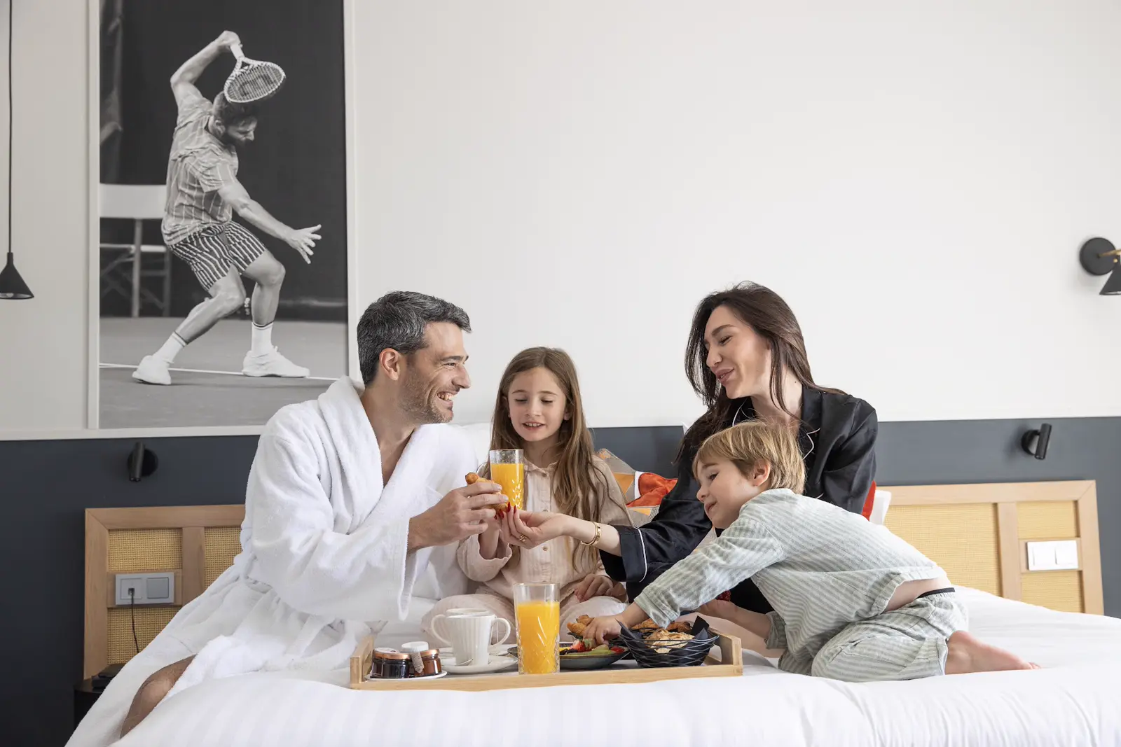 Famille partageant un petit-déjeuner au lit dans une chambre de l’hôtel