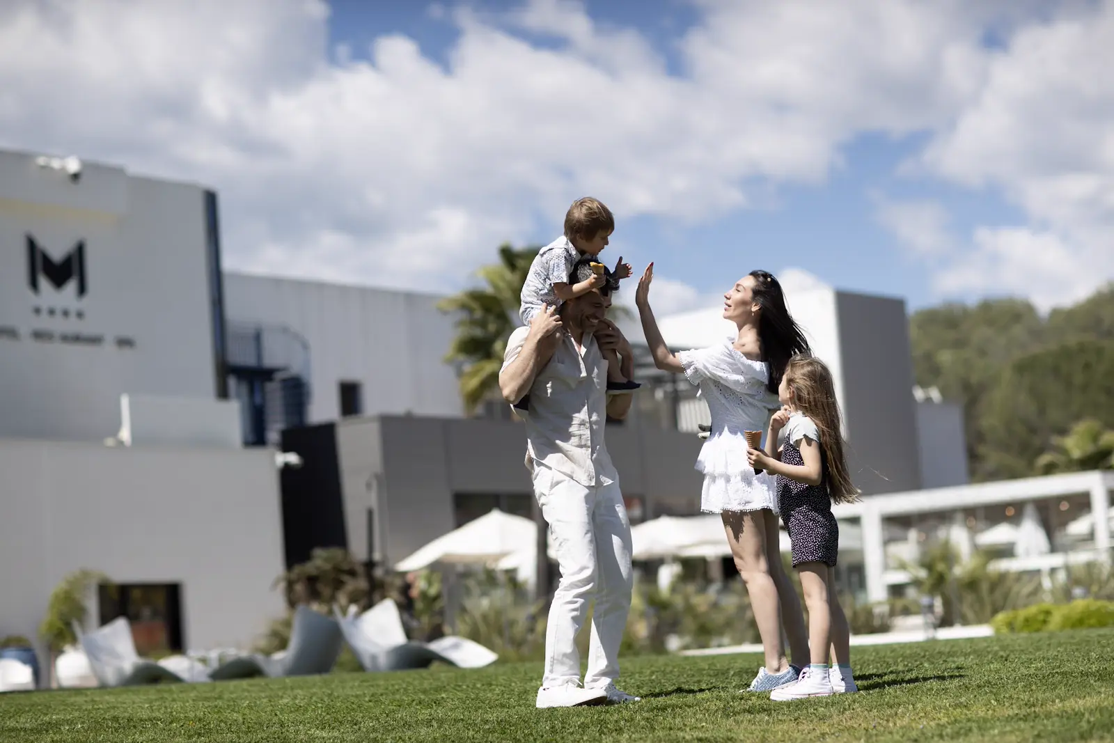 Famille jouant sur la pelouse du resort devant l’hôtel