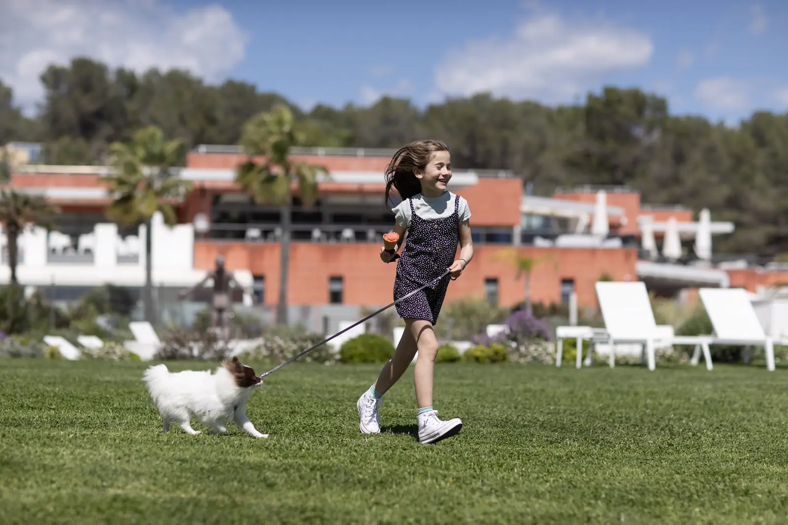 Fillette courant avec son chien sur la pelouse du resort