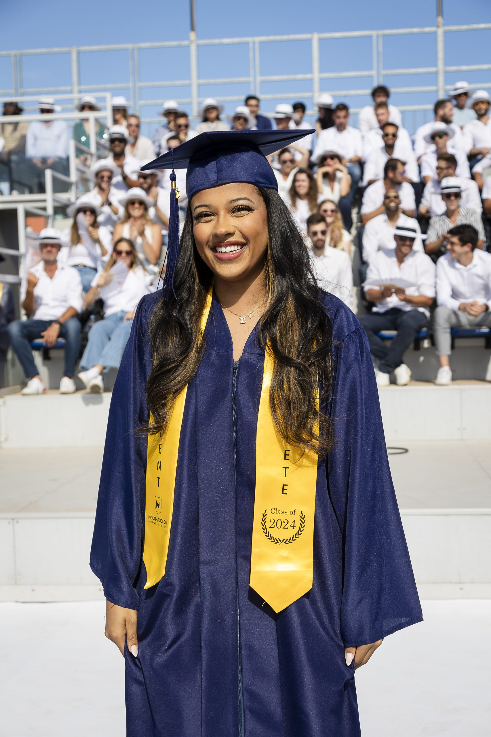 Diplômée de la section américaine souriante en toge et toque à la Mouratoglou International School
