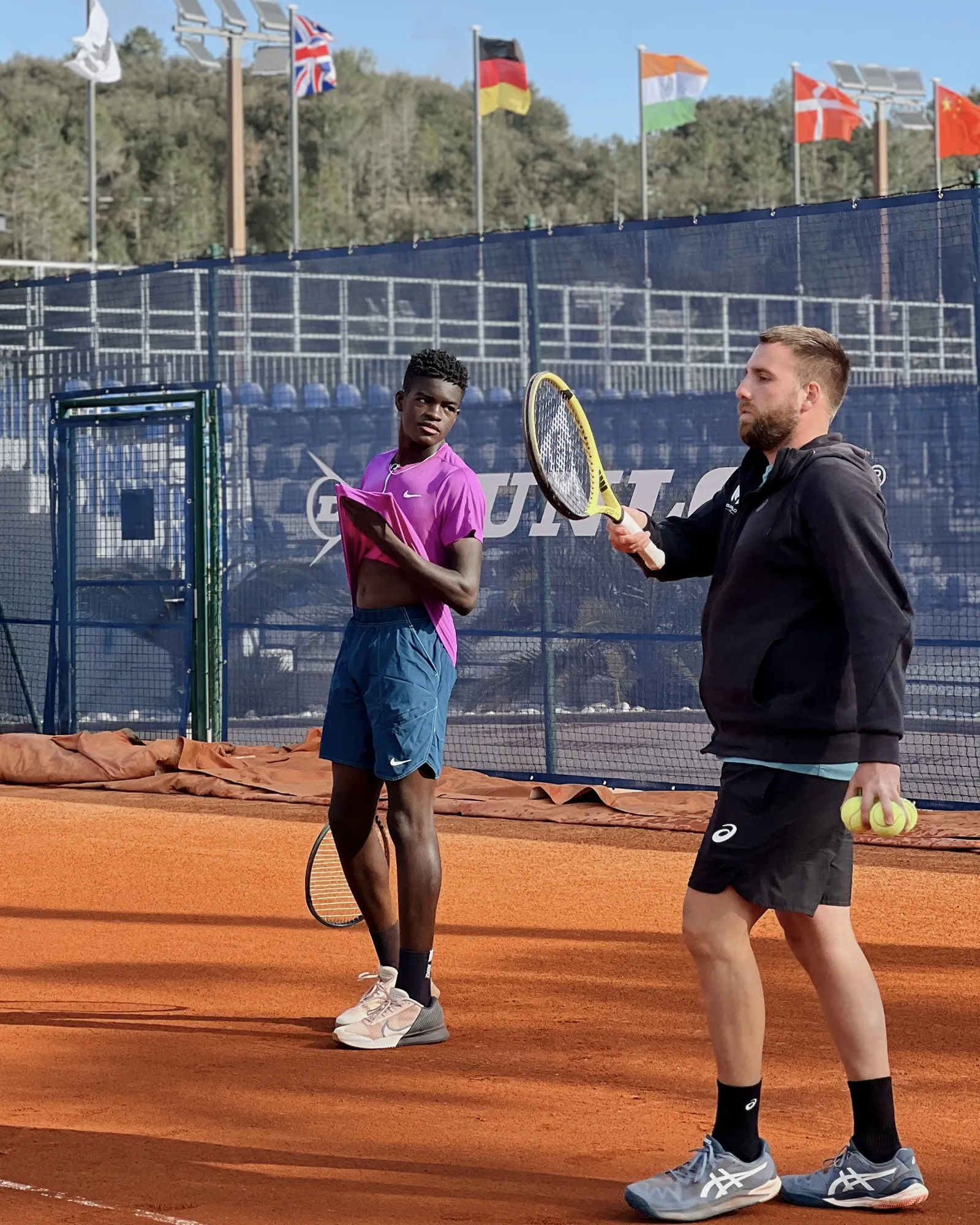 Carel Ngounoue discutant avec un coach sur un court en terre battue