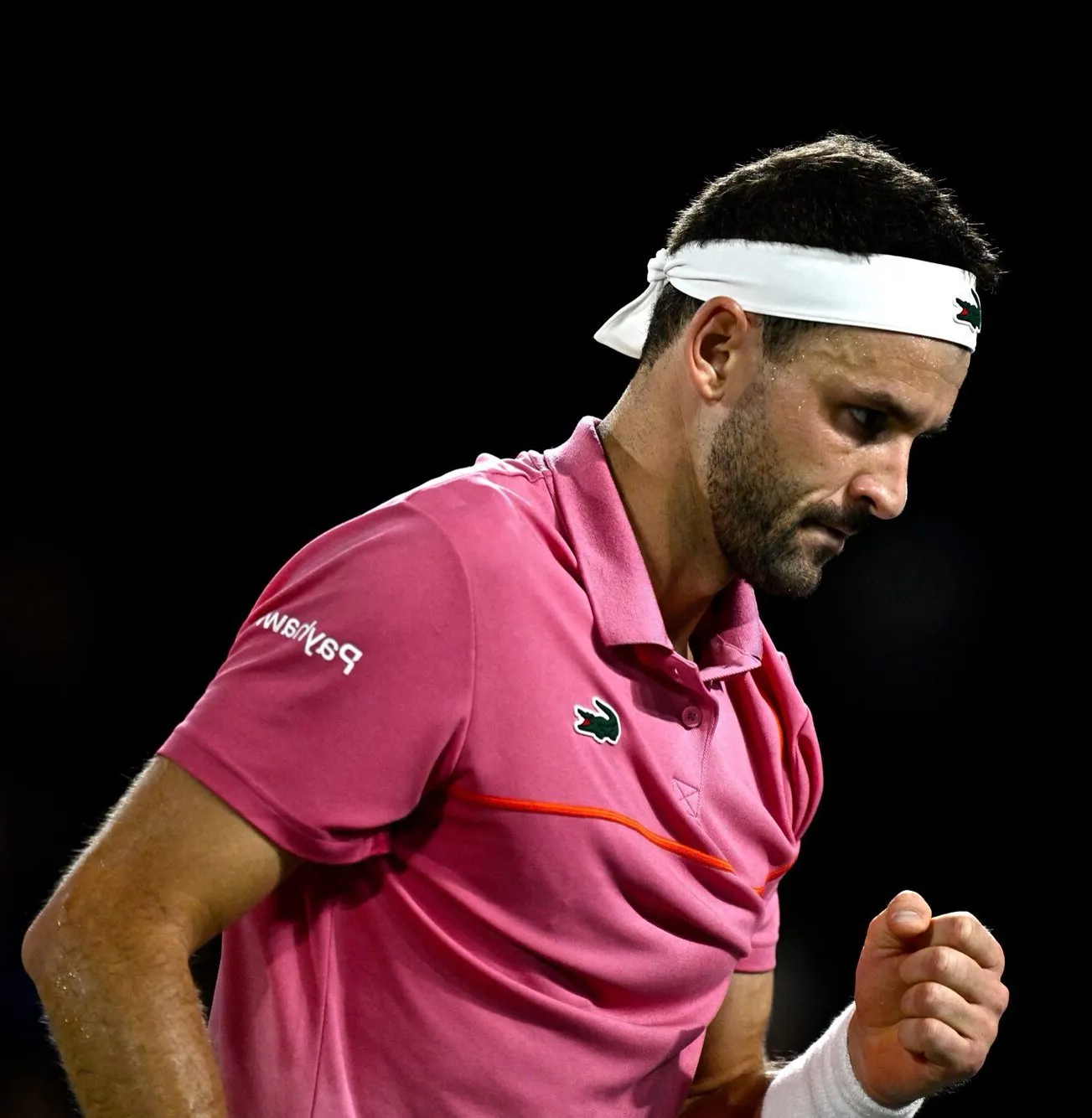 Grigor Dimitrov con una camiseta rosa apretando el puño