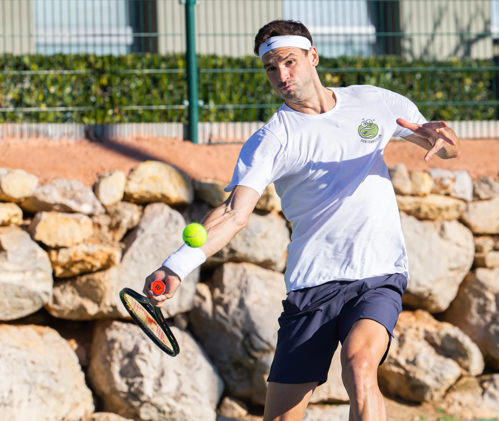 Grigor Dimitrov golpeando una derecha en una pista de tierra batida de la academia