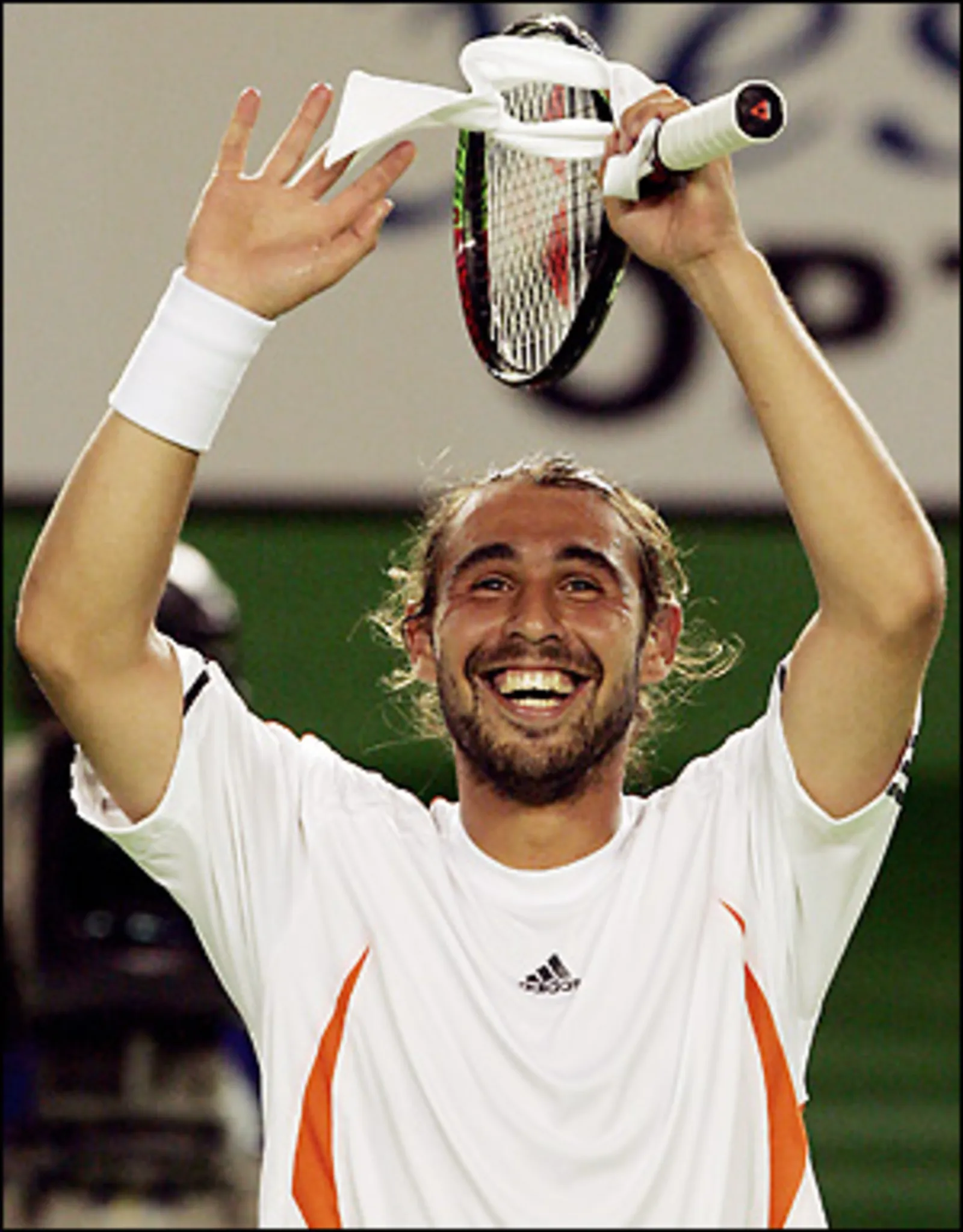 Marcos Baghdatis raising his racket and celebrating with a big smile