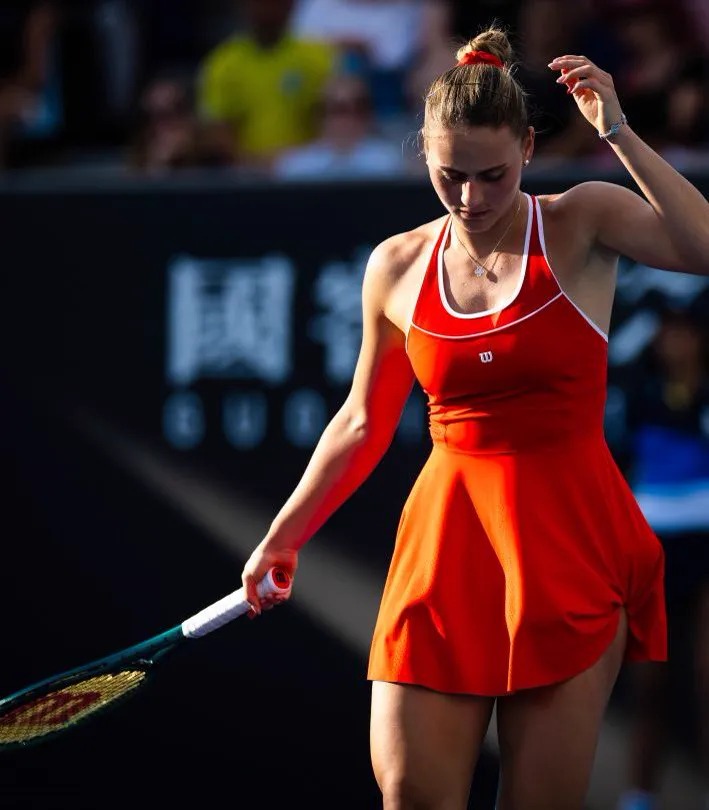 Marta Kostyuk in einem roten Kleid zwischen zwei Punkten