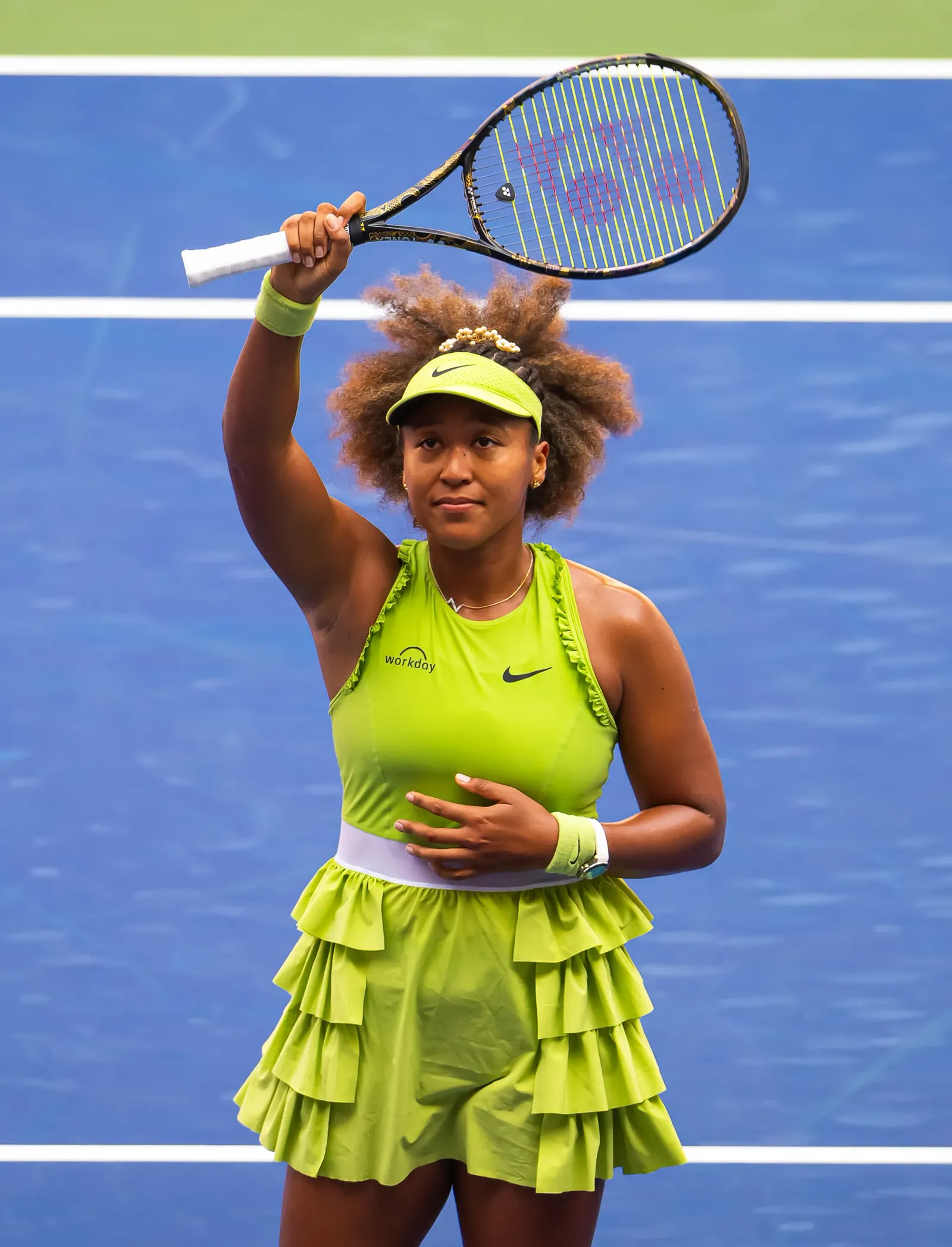Naomi Osaka smiling on court with her racket raised