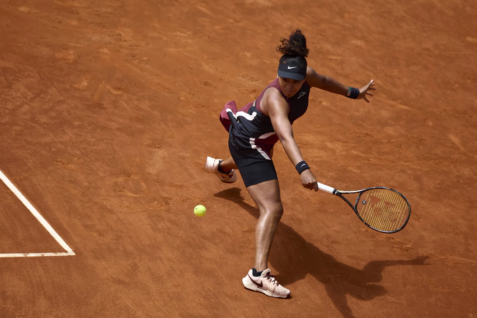 Naomi Osaka stretching for a forehand on clay