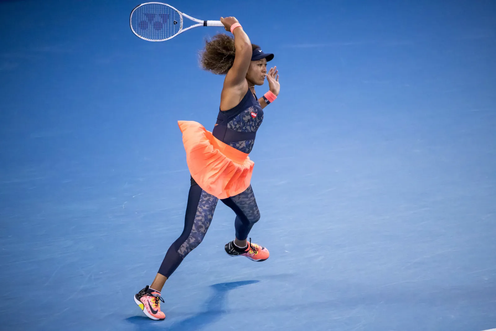 Naomi Osaka serving on a blue hard court