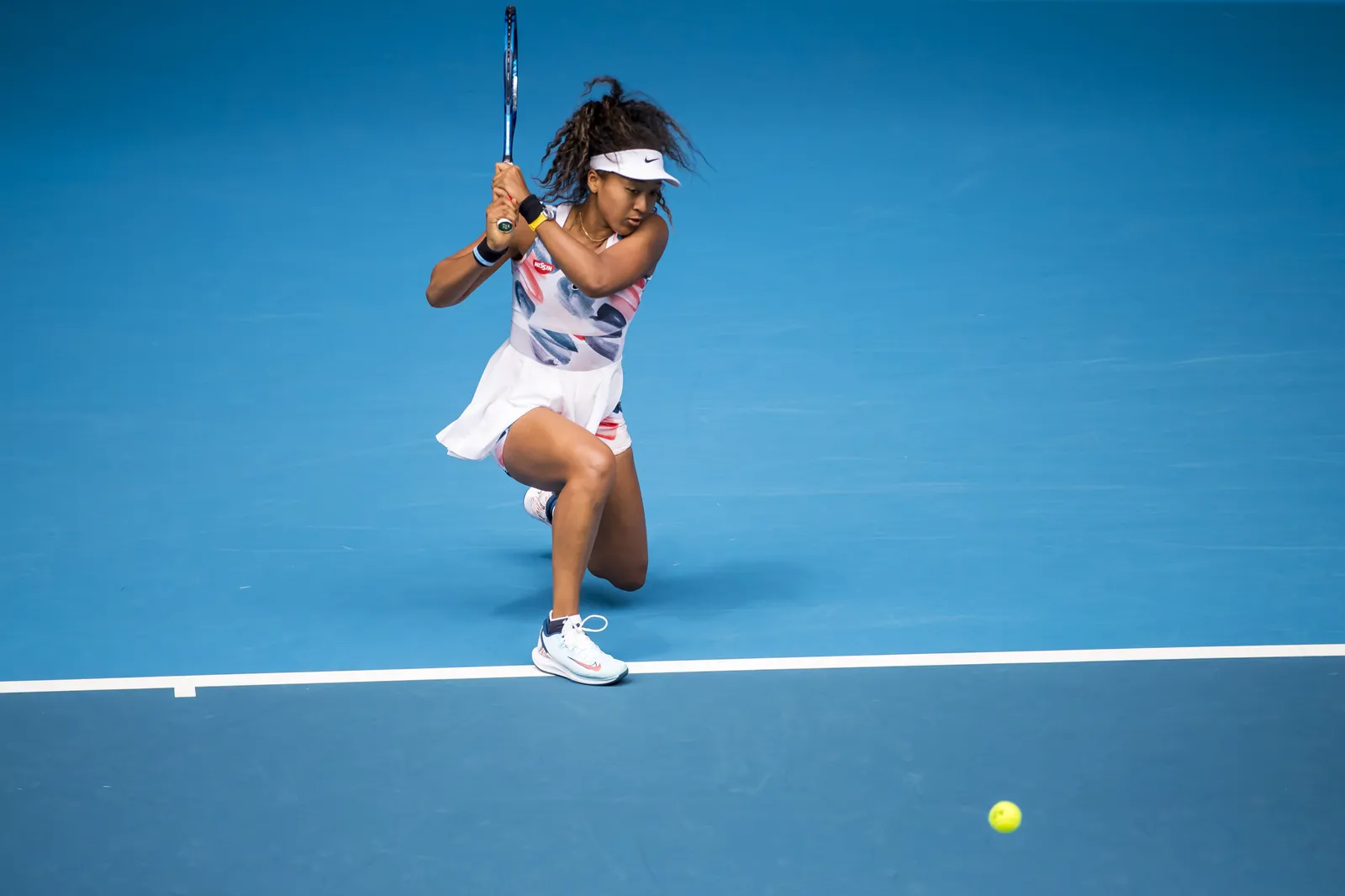 Naomi Osaka hitting a forehand on a blue hard court