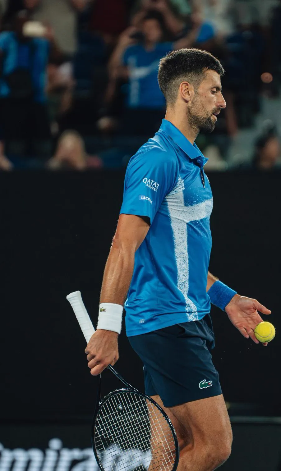 Novak Djokovic walking on court with a ball in his hand