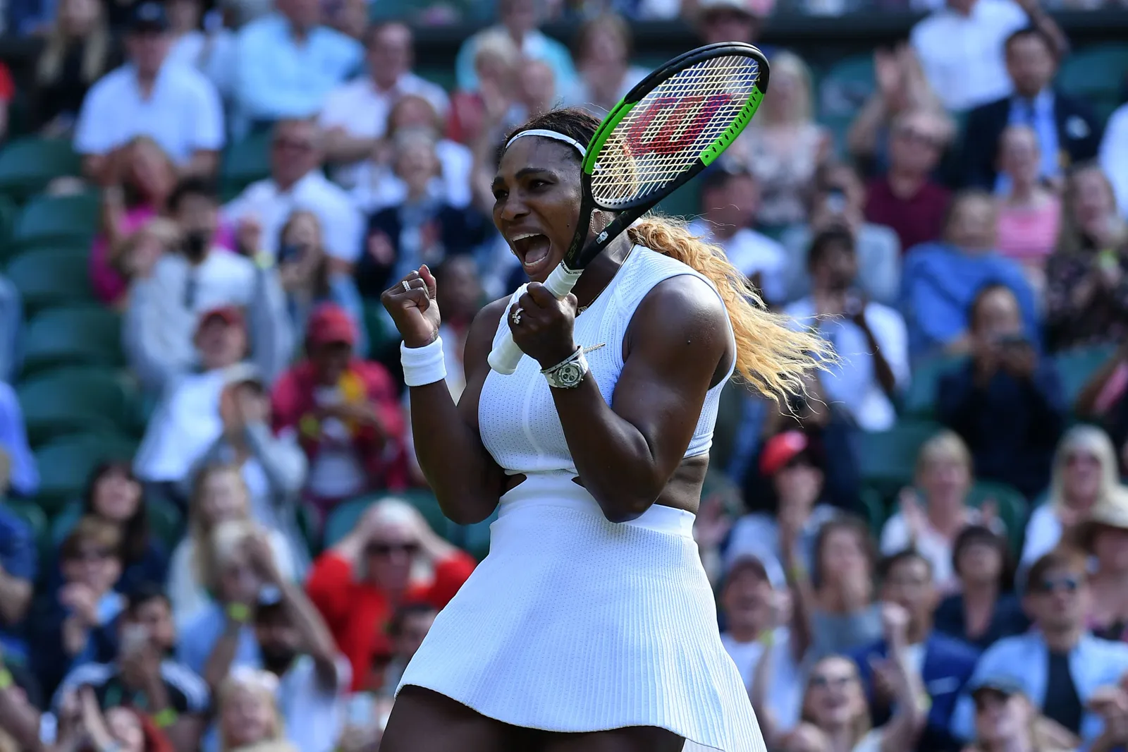 Serena Williams célébrant une victoire en robe blanche devant le public