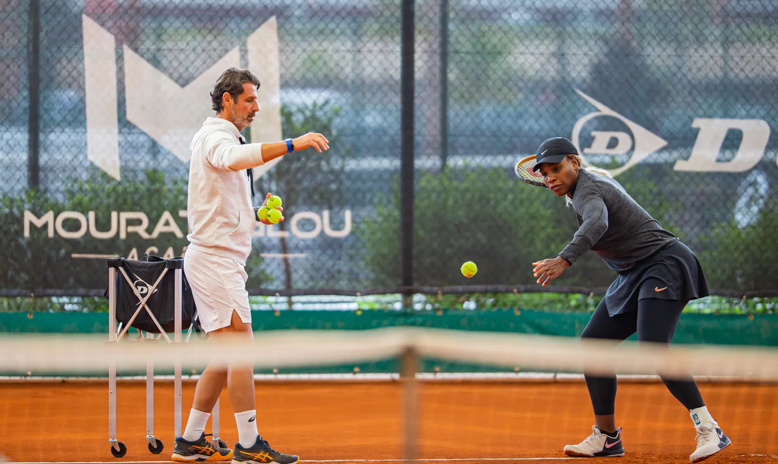Patrick Mouratoglou envoyant des balles à Serena Williams sur un court en terre battue de l’académie