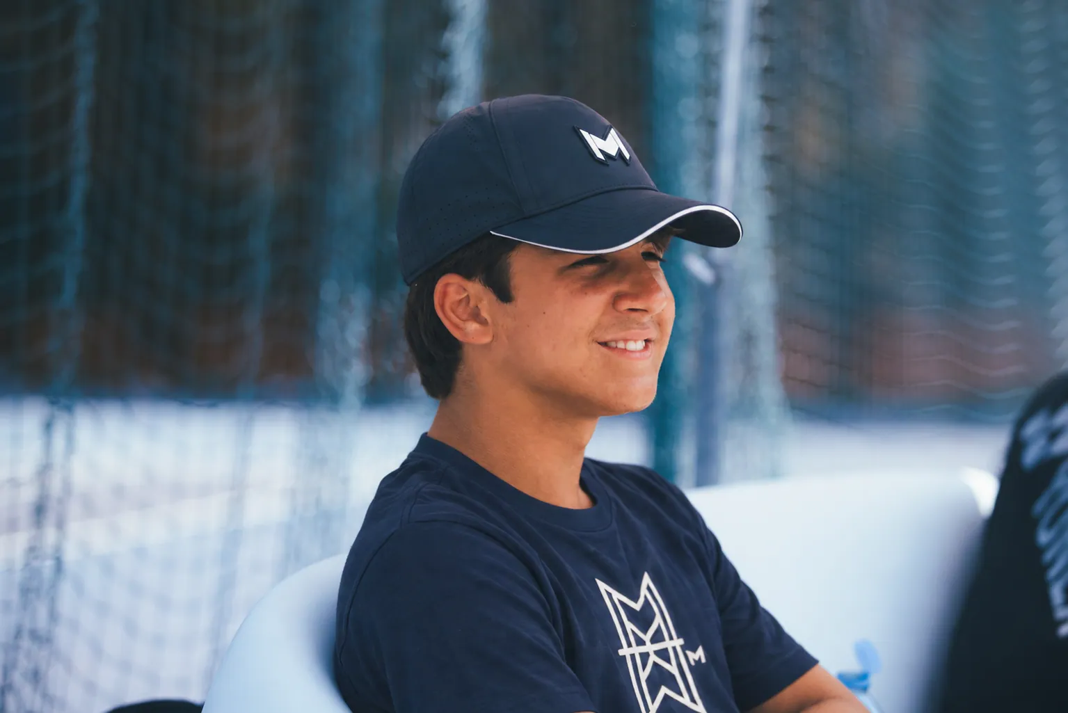 Smiling boy in a navy Mouratoglou graphic T-shirt and cap