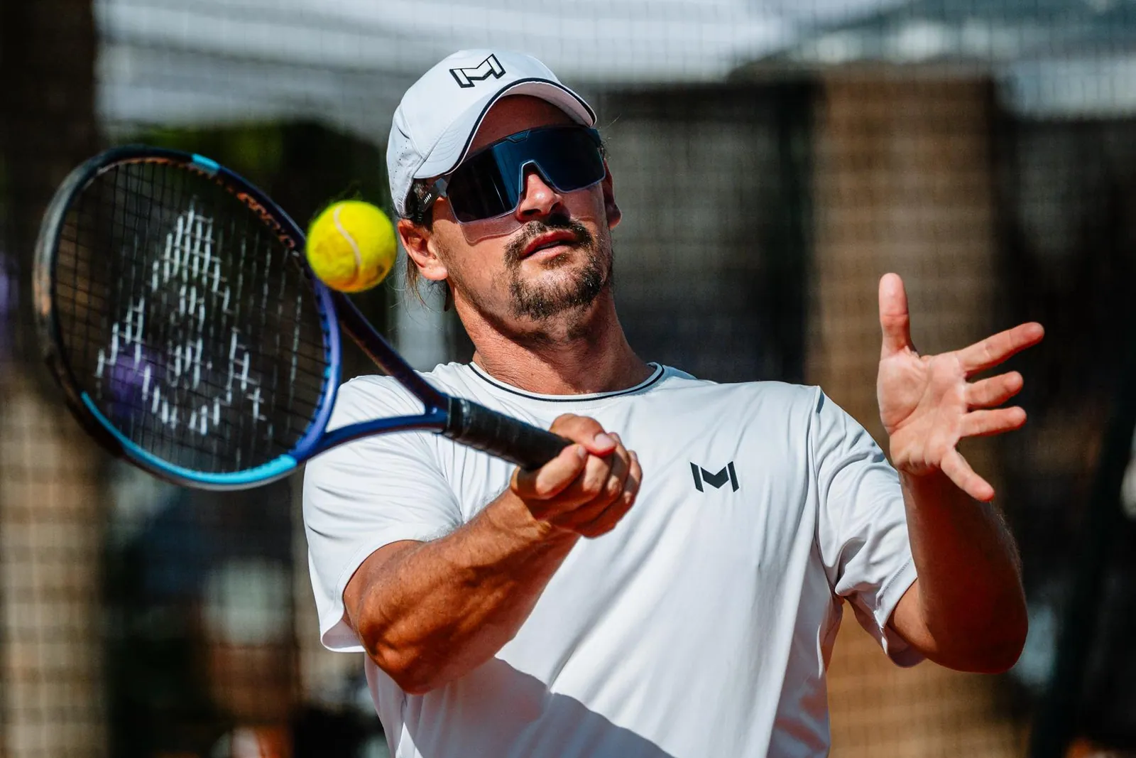Jugador adulto golpea una derecha durante un campamento de tenis de invierno en la Mouratoglou Academy
